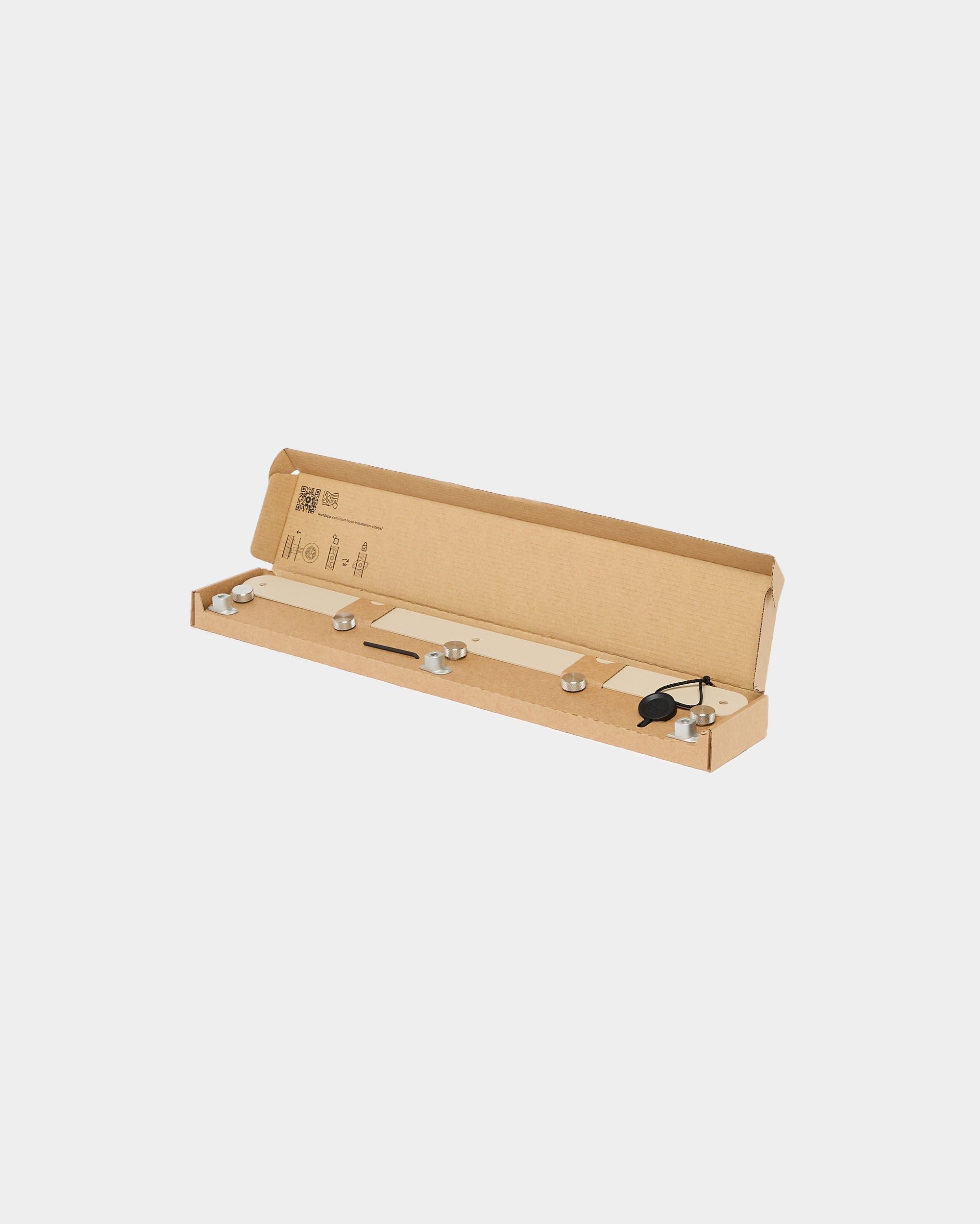 A long rectangular cardboard box with an open lid, holding a strip light fixture and power adapter accessory designed for installation with WoodUpp acoustic panels.